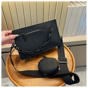 Detail of black PU crossbody bag with thick chain decor and small round coin purse charm