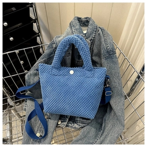 Bolso saco azul con textura de burbujas y botón sobre una chaqueta de mezclilla