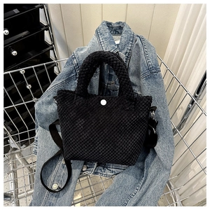Detalle de bolso negro con textura popcorn, broche plateado y correa ajustable