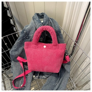 Detalle de bolso bucket de pana rosa fucsia en una cesta de metal