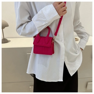 Close-up van fuchsia mini crossbodytas met steenpatroon en goudkleurige hardware