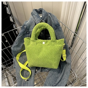 Detalle del bolso de pana verde brillante con textura de punto y cierre de botón
