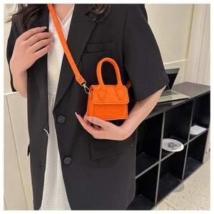 Detail van de feloranje mini-tas met krokodillenpatroon op het model