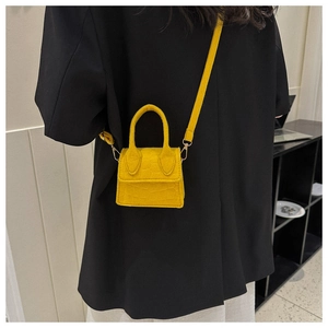 Gele mini crossbodytas met steenpatroon gedragen op een stijlvol zwart colbert