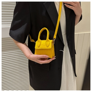 Detail van heldergele mini-crossbodytas met krokodillenpatroon en gouden hardware