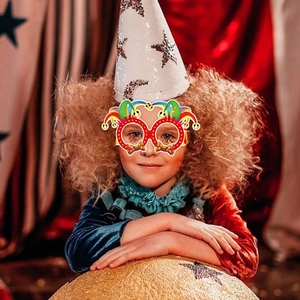 Close-up of child wearing colorful carnival clown paper glasses with circus decorations