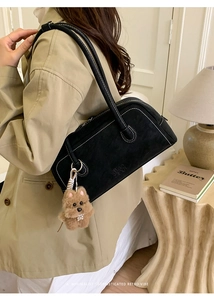Détail du sac à bandoulière noir avec coutures blanches contrastées et breloque peluche