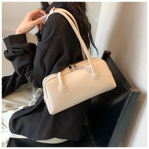 Detail view of cream shoulder bag featuring embossed texture and premium zip closure