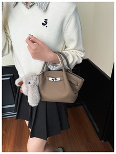 Detailed view of brown leather bucket bag with silver buckle and grey bunny charm accessory