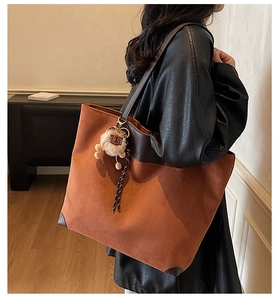 Detailed side view of vintage suede tote bag with brown leather trim and plush lion charm