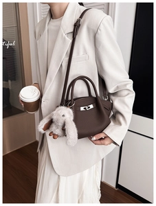 Detail of dark brown lychee leather bucket bag with silver buckle and rabbit plush charm