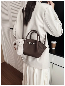 Detail of dark brown lychee leather bucket bag with silver buckle and plush rabbit charm
