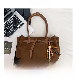 Detail of dark brown faux suede tote bag featuring metallic buckle and colorful tassel charm