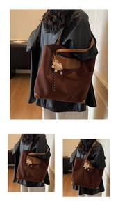 Detail of vintage brown suede tote bag with leather trim and white plush pom-pom charm