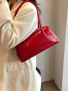 Elegant red faux leather shoulder bag with a high-gloss finish and stylish baguette design