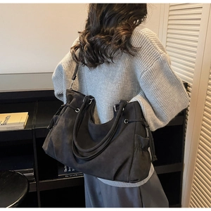 Detalle del bolso tote de ante negro con cordones ajustables y correa para el hombro