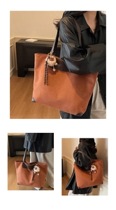 Detail of vintage suede tote bag in brown with contrasting leather trim and plush tassel