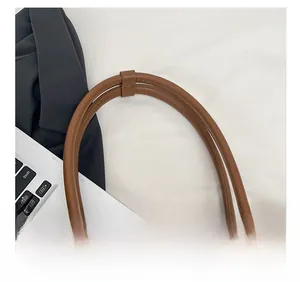 Detail of coffee brown tote bag showing dual faux leather shoulder straps with secure fastener