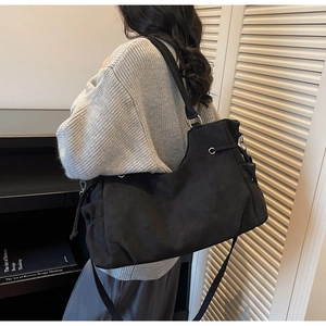 Detalle de bolso tote negro de gran capacidad con cordones y correas ajustables