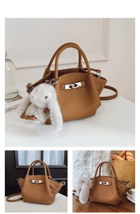 Detail of brown litchi pattern bucket bag with silver twist lock and plush rabbit charm