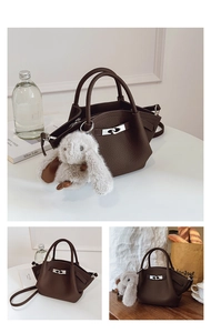 Detail of dark brown pebble leather tote bag with silver S-lock and plush bunny charm