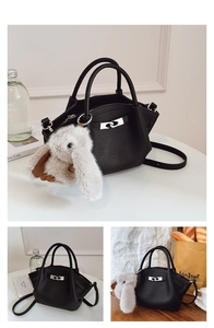 Detail of black lychee grain leather bucket bag with silver buckle and rabbit charm