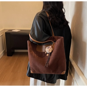 Detail view of large brown faux suede tote bag with leather trim and plush charm pendant