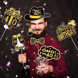 Black and gold 40th birthday photo booth props set held by a man at a party