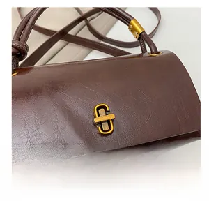 Close-up of vintage brown leather handbag featuring a premium golden metal twist lock