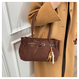 Detail of dark brown suede tote bag with bohemian bead tassels on wool coat