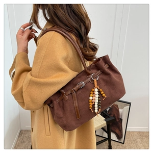 Close-up of vintage brown suede tote bag with ethnic wooden bead charm detail