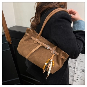 Detail of vintage brown suede tote bag with metal buckle and colorful beaded charm