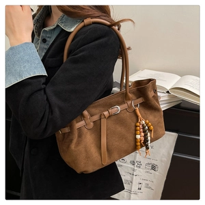 Close-up of brown faux suede tote bag with decorative strap and beaded tassel pendant