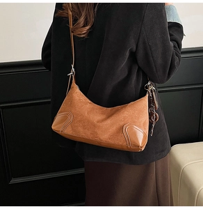 Borsa a spalla in camoscio marrone con catena mostrata su un modello in studio