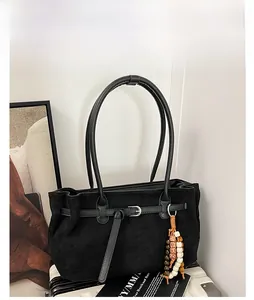 Detail of black faux suede tote bag with metal buckle and colorful ethnic beaded tassel