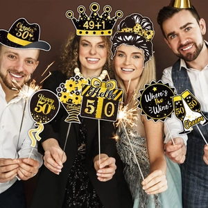 Close-up of 50th birthday party photo props with black gold glitter finish and wooden sticks
