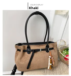 Detail of khaki suede tote bag with black leather straps and bohemian bead tassel