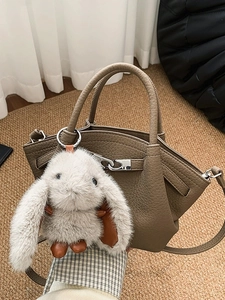 Brown lychee leather bucket bag with cute white plush bunny charm accessory