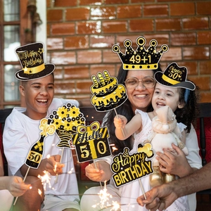 Close-up of 50th birthday photo booth props with black and gold glitter paper decorations