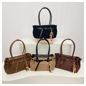 Detail of four suede tote bags in various colors featuring beaded tassel and buckle straps
