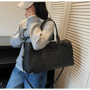 Detailed view of black canvas travel bag with reinforced straps and gold hardware
