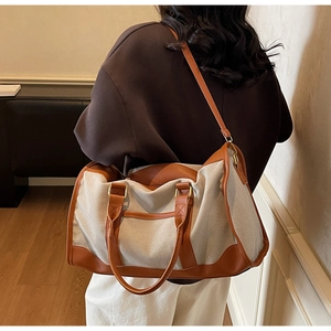 Canvas and leather travel bag shown on shoulder in a warm interior setting