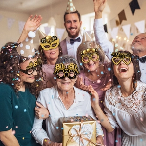 Close-up of five glittery 80th birthday party glasses with gold and black festive designs