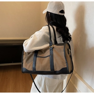 Canvas travel bag with leather trim shown on model for size perspective in indoor setting