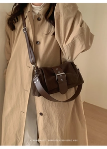 Détail d'un sac bandoulière rétro marron foncé avec boucle argentée porté avec un trench beige