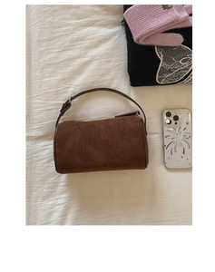 Detail of dark brown suede cylinder Boston bag with premium textured finish and handle