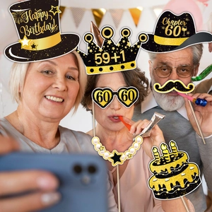 Close-up of 60th birthday party photo booth props with black and gold glitter accents