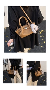 Detail der braunen Ledertasche mit Litschi-Muster und weißem Plüsch-Hasenanhänger