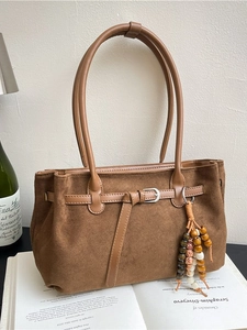 Vintage brown faux suede tote bag with decorative tassel on aesthetic book background