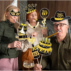 Seniors using black and gold 60th birthday photo booth props at a festive party setting